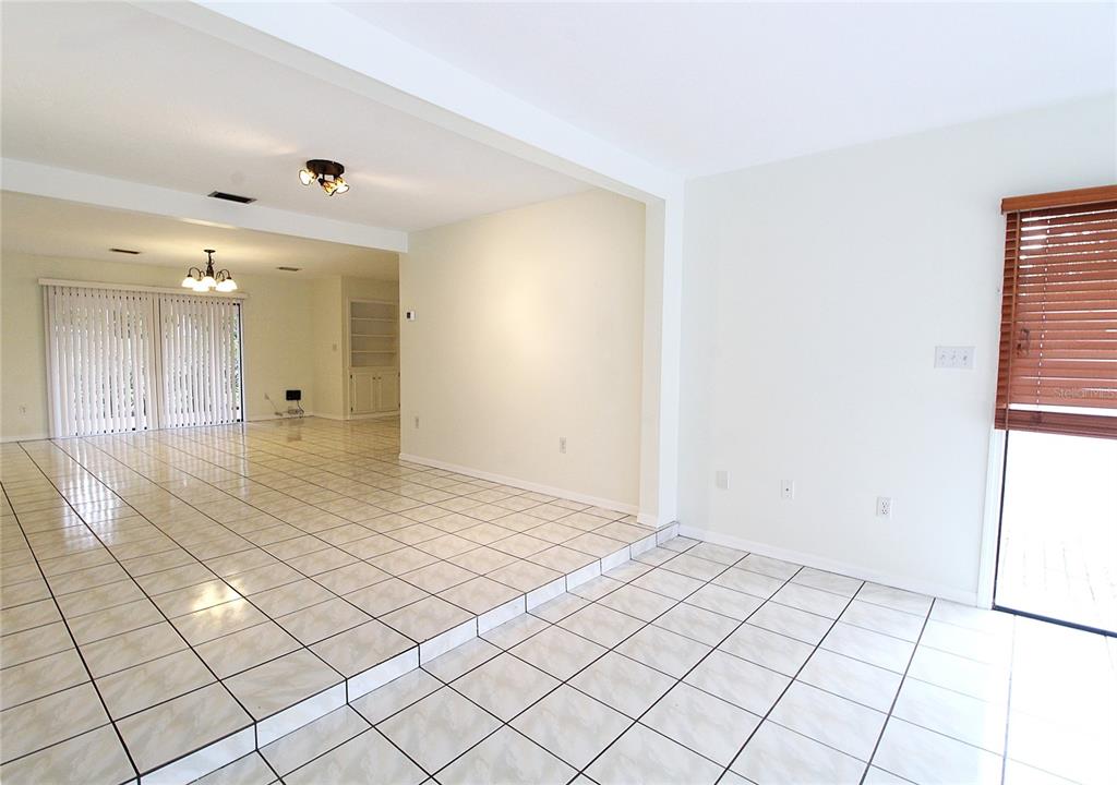 A living area with light-colored tile flooring, a sunken floor level, and sliding glass doors — 2516 E MILMAR DRIVE, SARASOTA, FL