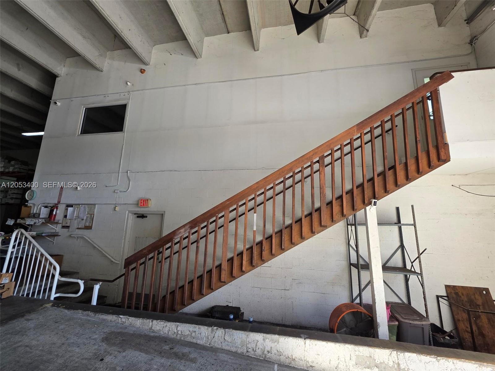 A wooden staircase with railings leads to an upper level in a warehouse space — 8555 NW 29th St, Doral FL 33122, DORAL, FL