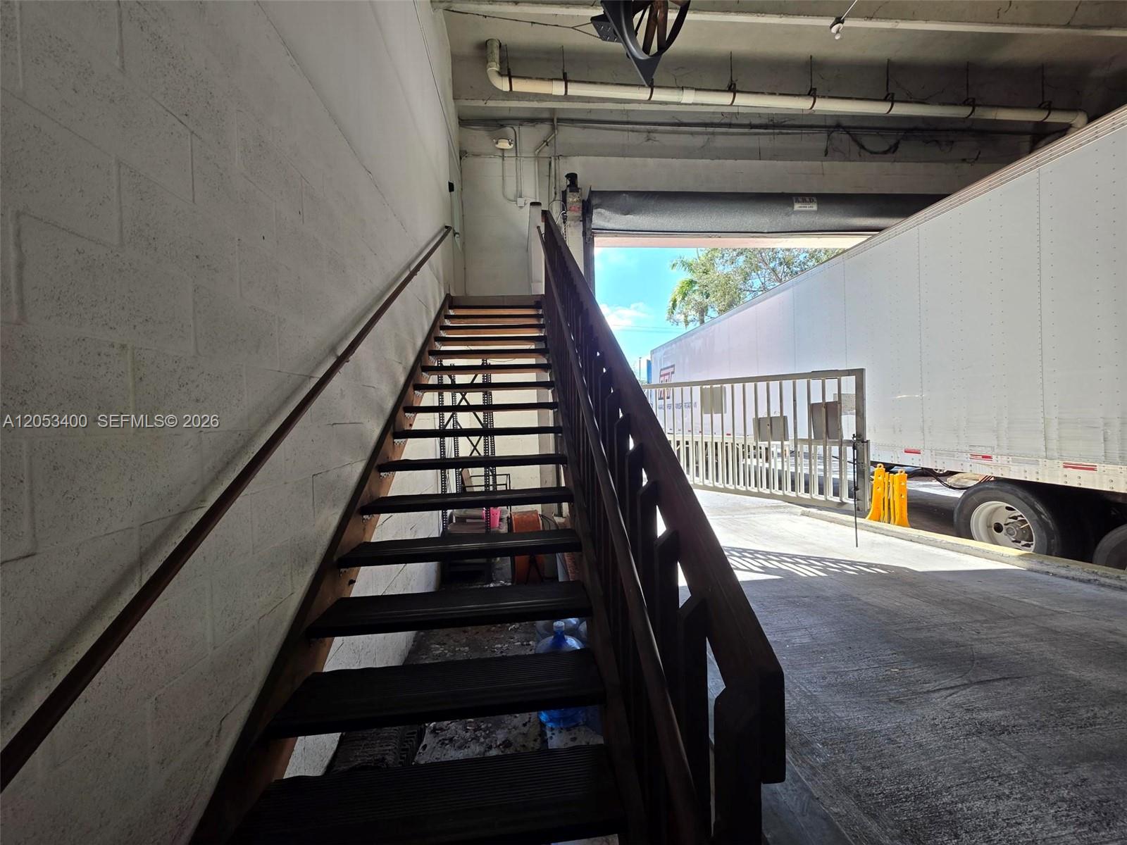 A set of wooden stairs leads upward inside a warehouse space next to a loading dock — 8555 NW 29th St, Doral FL 33122, DORAL, FL