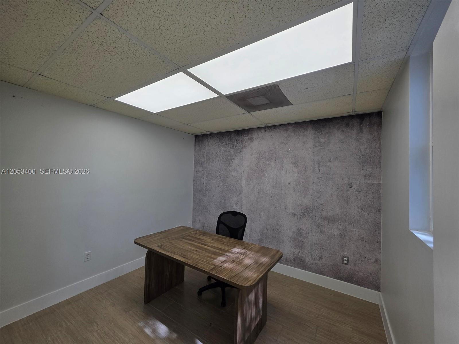 A small office features a wooden desk, a black chair, and a textured accent wall — 8555 NW 29th St, Doral FL 33122, DORAL, FL