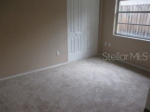 A bedroom with beige walls, light-colored carpet, a white closet, and a window with blinds — 4851 BILLY DIRECT LANE, LUTZ, FL