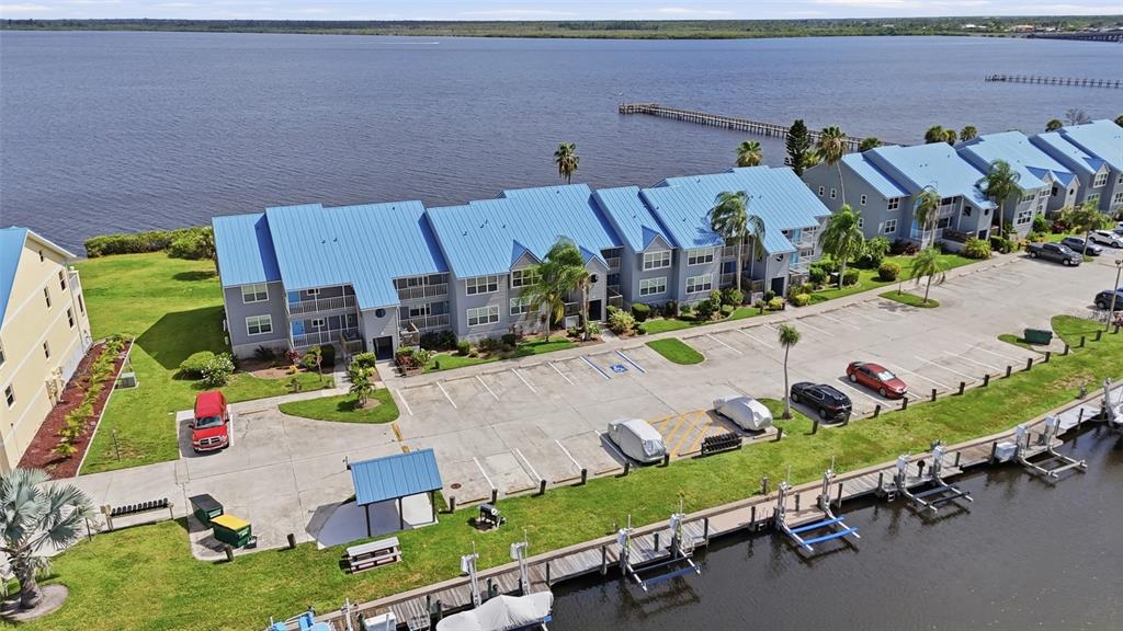 An aerial view shows a multi-story apartment building with a blue metal roof near water — 4410 WARREN AVENUE UNIT 412, PORT CHARLOTTE, FL