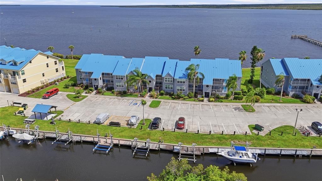An aerial view shows waterfront apartment buildings with blue metal roofs and a parking lot — 4410 WARREN AVENUE UNIT 412, PORT CHARLOTTE, FL