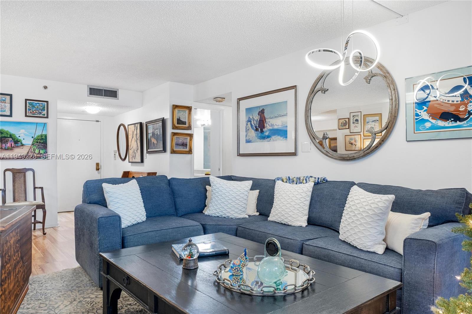 A living room features a blue sectional sofa, a dark coffee table, and wall art — 4000 Towerside Ter # 301, Miami FL 33138, MIAMI, FL