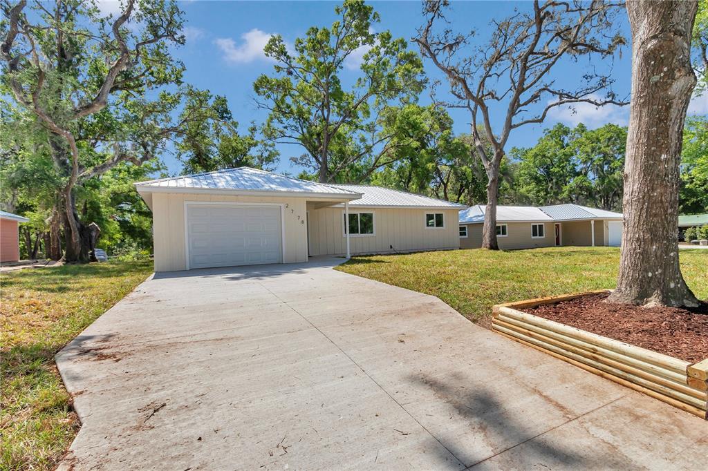 A single-story house with a white metal roof, light siding, and a concrete driveway — 2778 W CYPRESS DRIVE, DUNNELLON, FL