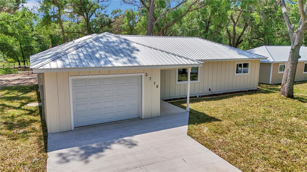 A single-story house with light yellow vertical siding, a metal roof, and a garage — 2778 W CYPRESS DRIVE, DUNNELLON, FL