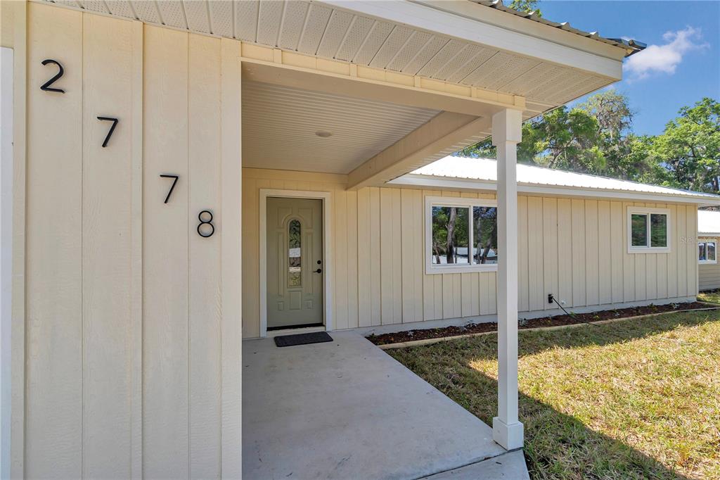 The exterior of a light yellow house features a covered entryway and a front door — 2778 W CYPRESS DRIVE, DUNNELLON, FL