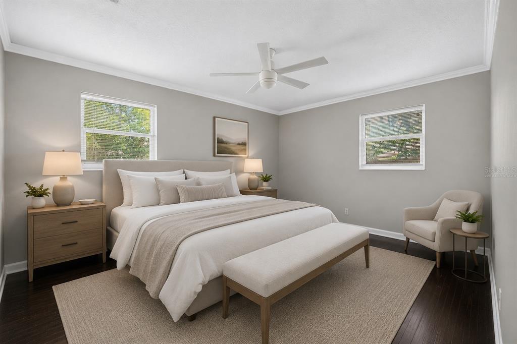 A bedroom with a king bed, two nightstands, a bench, and an armchair on hardwood floors — 1543 REDBUD COURT, ORANGE PARK, FL