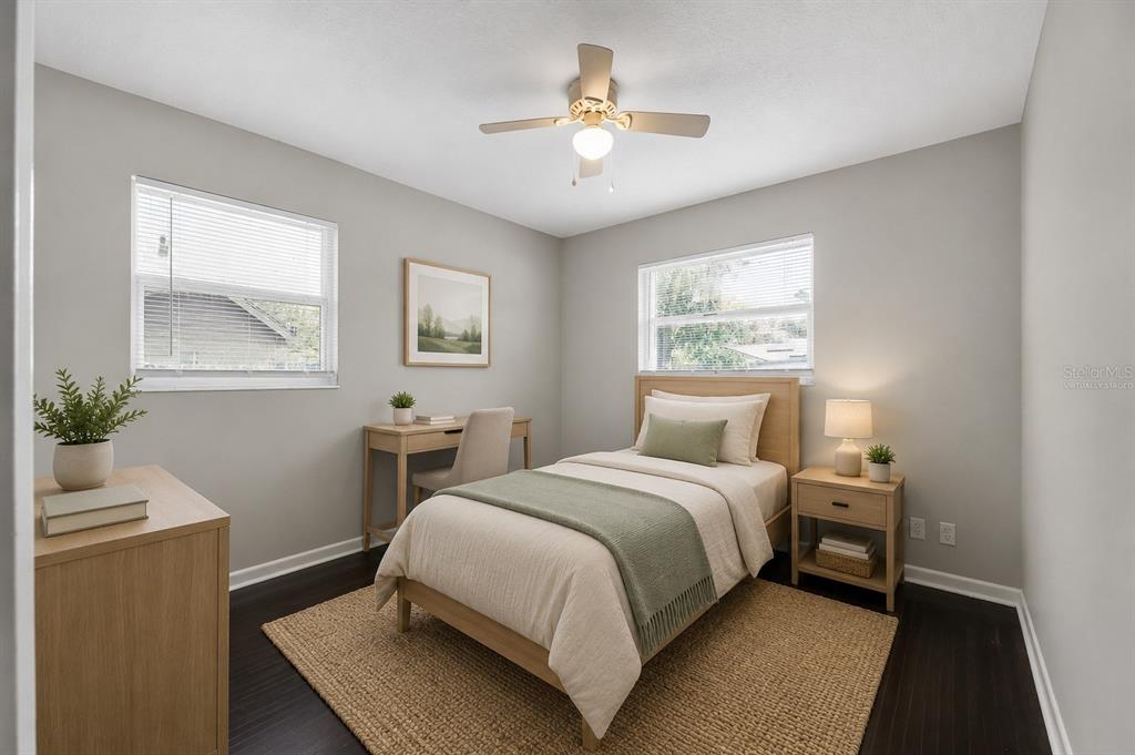 A bedroom with a single bed, desk, dresser, and two windows with light gray walls — 1543 REDBUD COURT, ORANGE PARK, FL