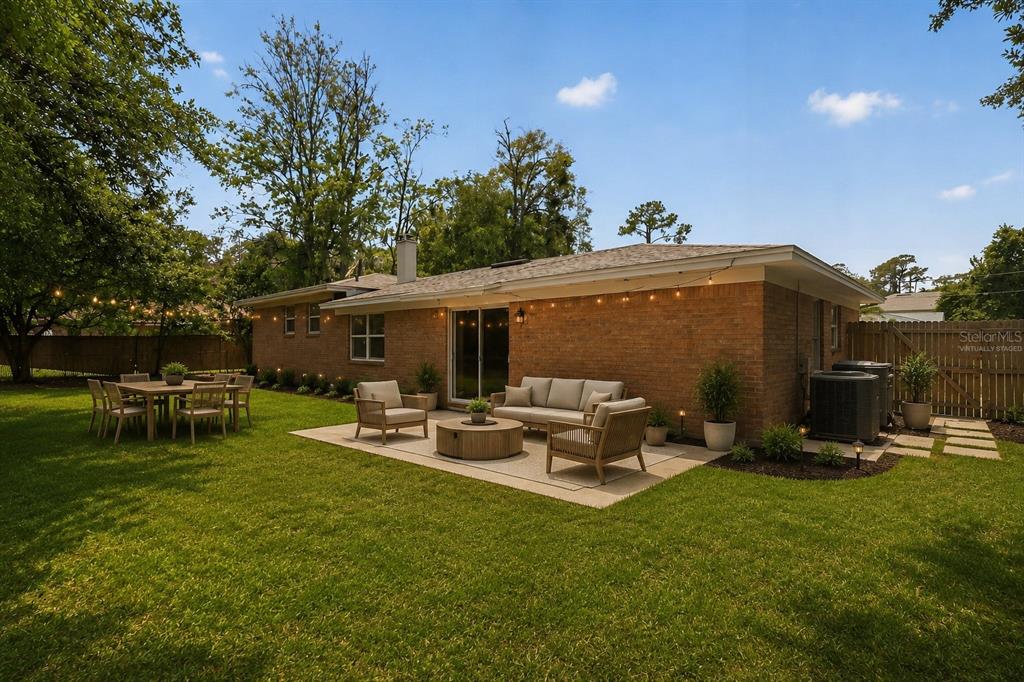 A brick house exterior features a patio with outdoor furniture and a grassy backyard — 1543 REDBUD COURT, ORANGE PARK, FL