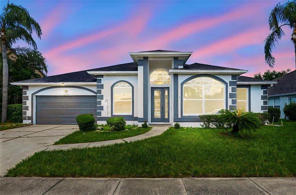 A single-story house with a gray garage, white stucco walls, and a central arched entryway — 12714 TOPSFIELD DRIVE, ORLANDO, FL