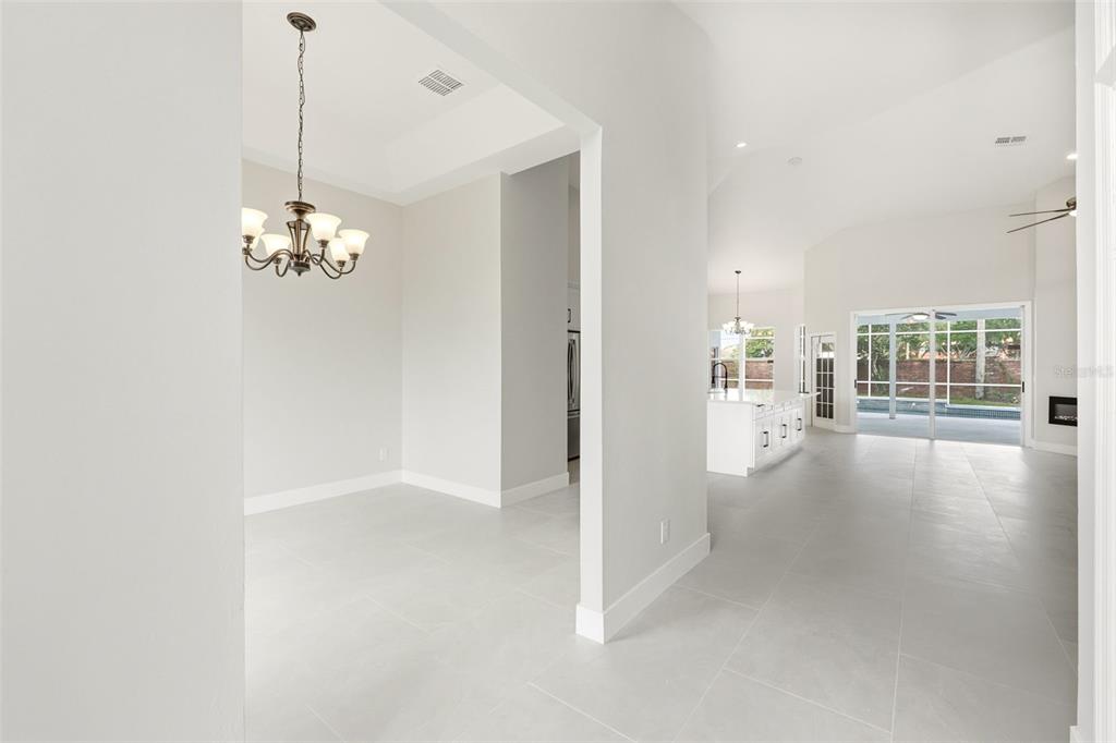 A bright, open-concept interior features a dining area with a chandelier and a white kitchen — 12714 TOPSFIELD DRIVE, ORLANDO, FL