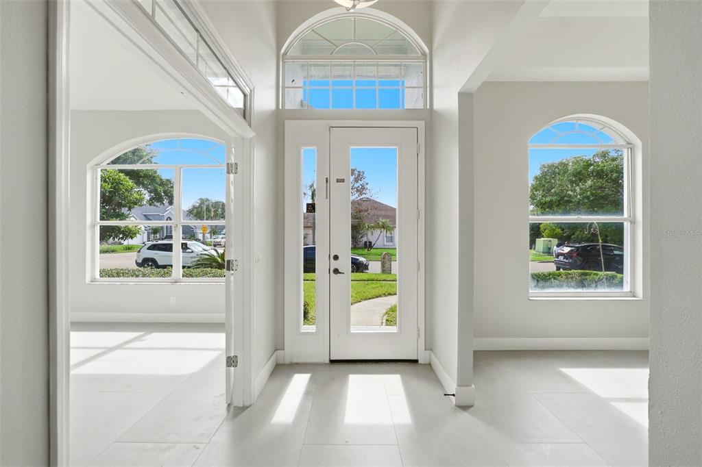 A bright entryway features a white front door with a transom window and tile flooring — 12714 TOPSFIELD DRIVE, ORLANDO, FL