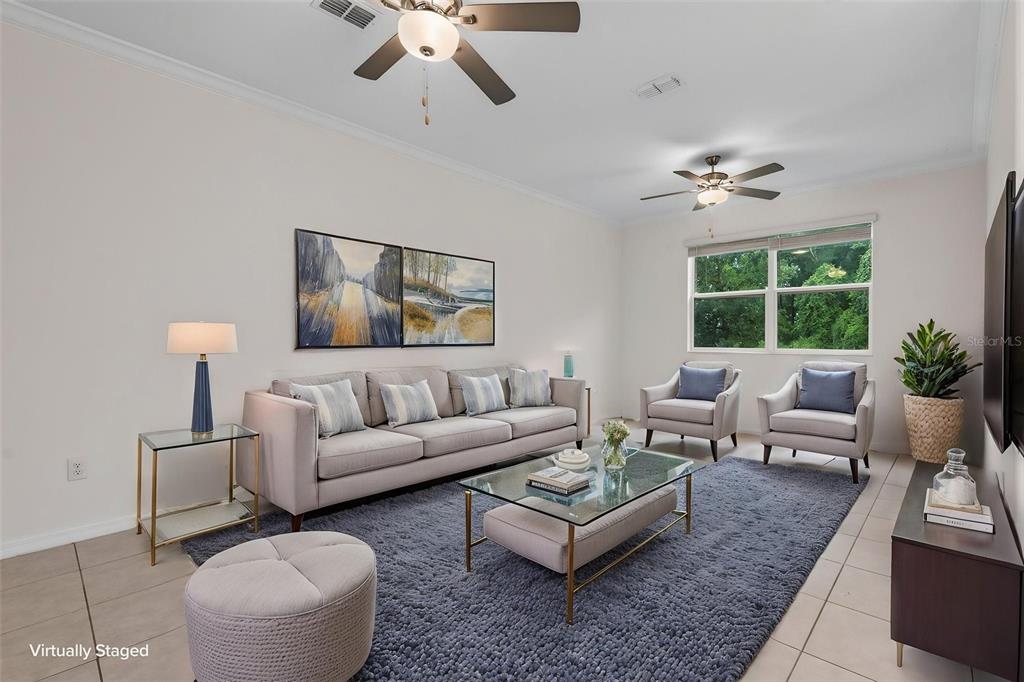 A living room with a sofa, two armchairs, a glass coffee table, and ceiling fans — 17474 NECTAR FLUME DRIVE, LAND O LAKES, FL
