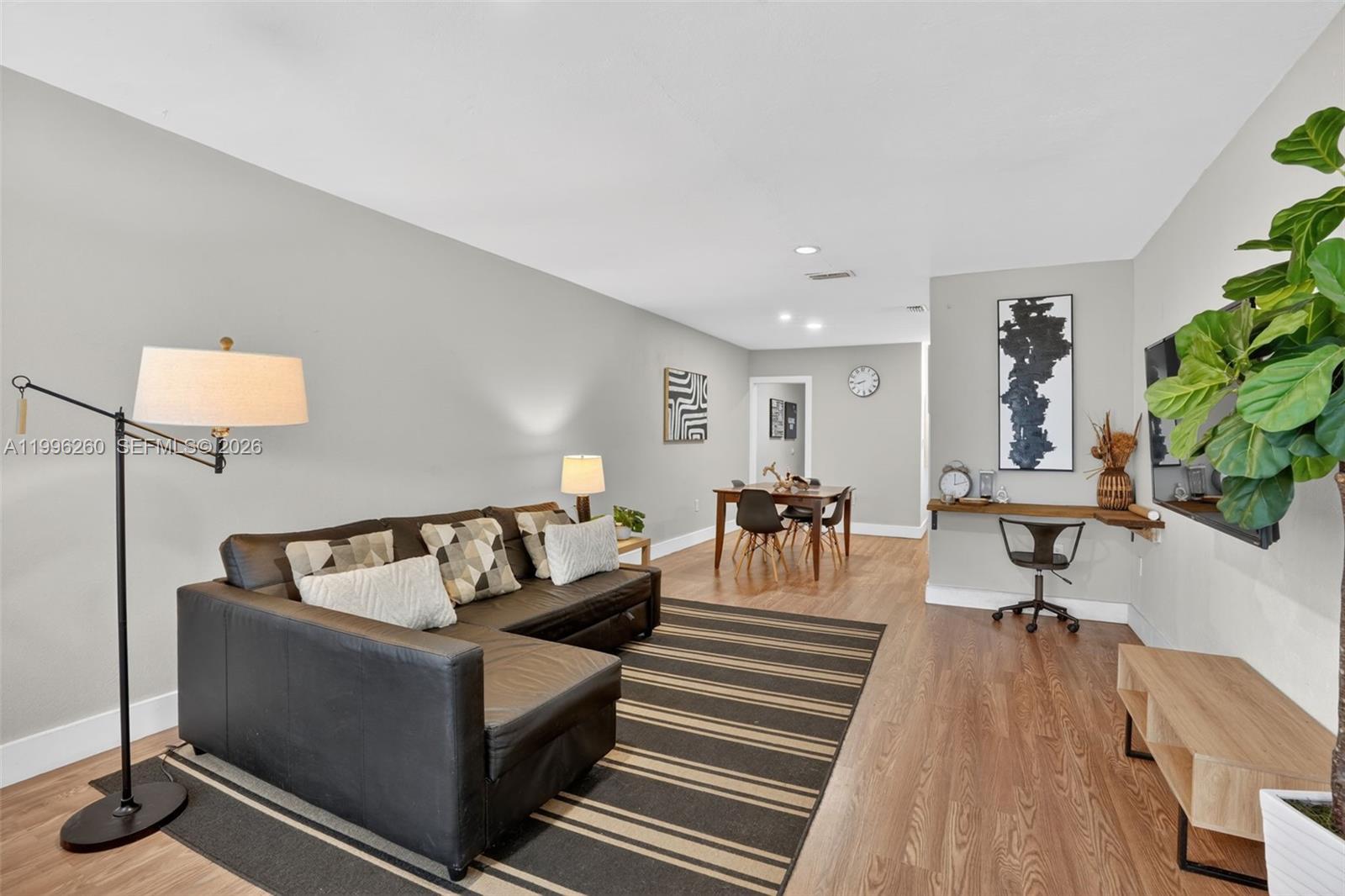 A living room features a dark sectional sofa, a dining area, and a wall-mounted desk — 7811 NE 10th Ct, Miami FL 33138, MIAMI, FL
