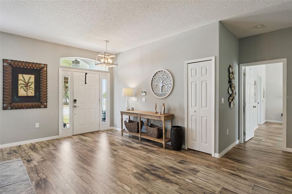 A bright entryway features wood-look flooring, a white front door, and a wooden console table — 515 JUNE AVENUE, HAINES CITY, FL