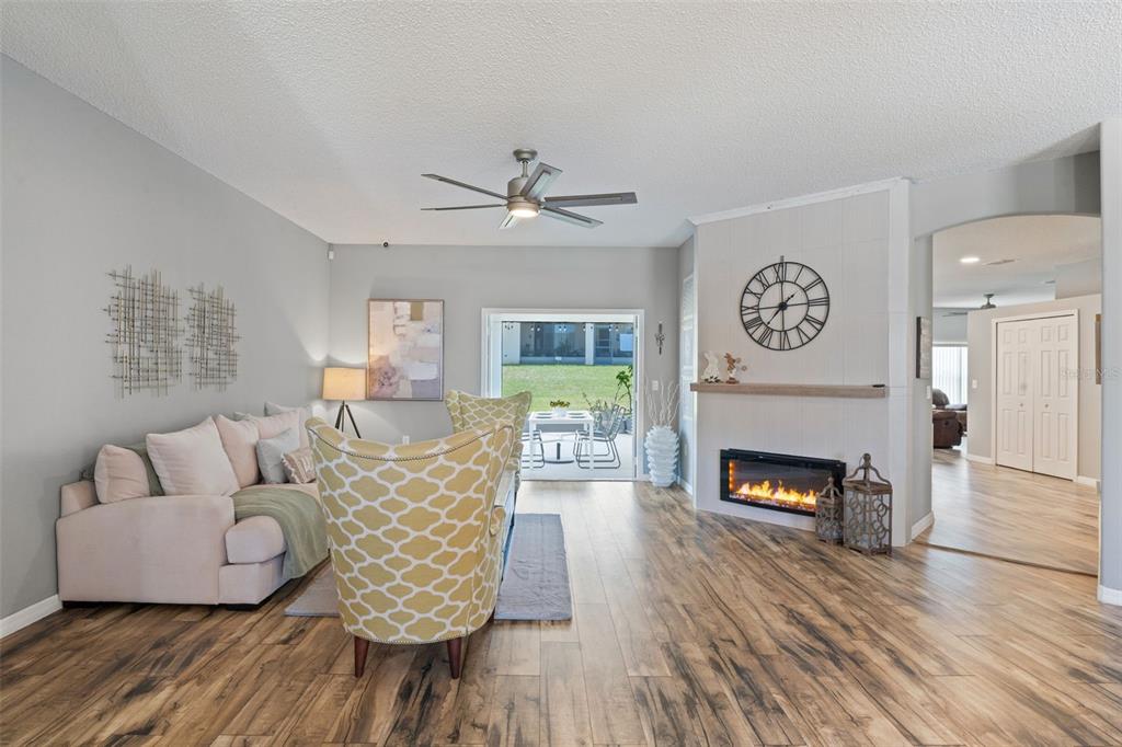 A living room features wood-look flooring, a fireplace, a ceiling fan, and a sliding glass door — 515 JUNE AVENUE, HAINES CITY, FL