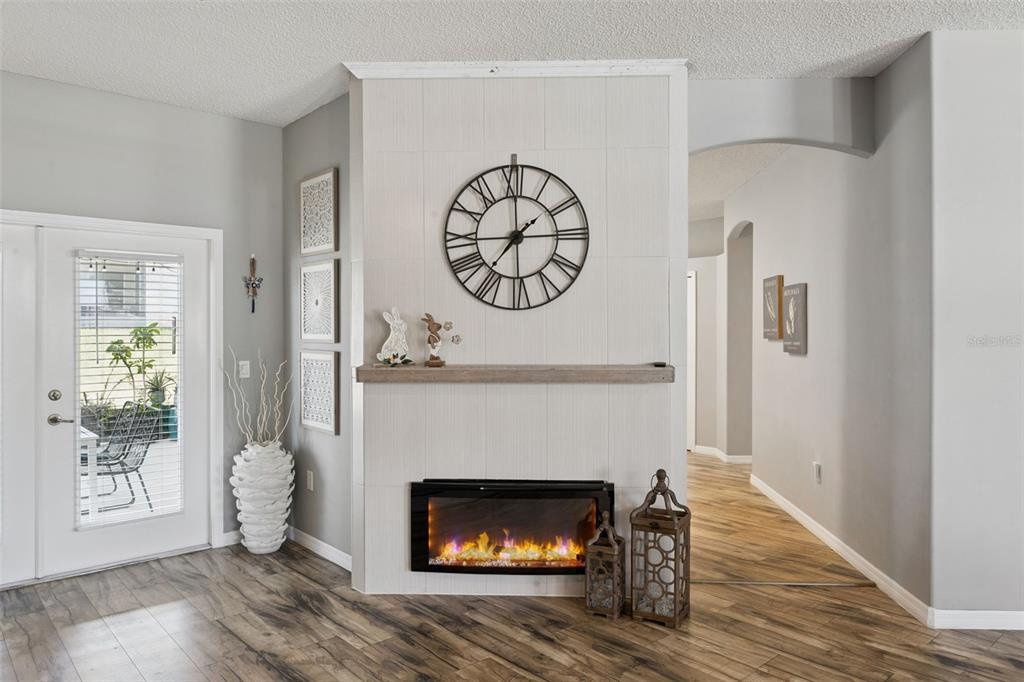 A living room features a central tiled fireplace wall with a clock and wood mantel — 515 JUNE AVENUE, HAINES CITY, FL