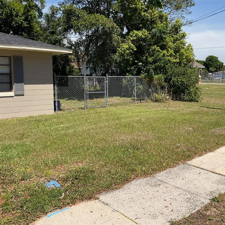 A side view of a house exterior with a chain-link fence and lawn — 385 LIME STREET UNIT 2, EATONVILLE, FL