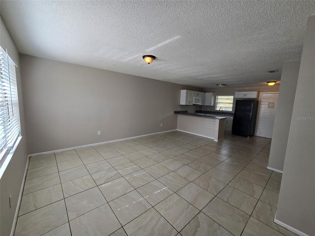An open-concept living and kitchen area features light-colored tile flooring and neutral wall paint — 385 LIME STREET UNIT 2, EATONVILLE, FL