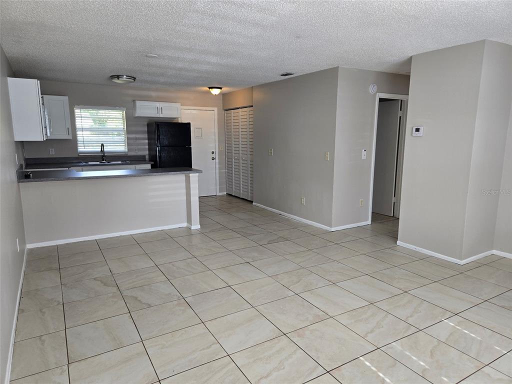An open-concept kitchen and living area features light tile flooring and neutral-toned walls — 385 LIME STREET UNIT 2, EATONVILLE, FL