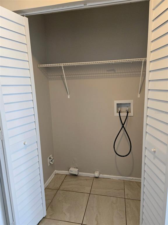 A laundry closet with a wire shelf, utility hookups, and tiled flooring behind louvered doors — 385 LIME STREET UNIT 2, EATONVILLE, FL