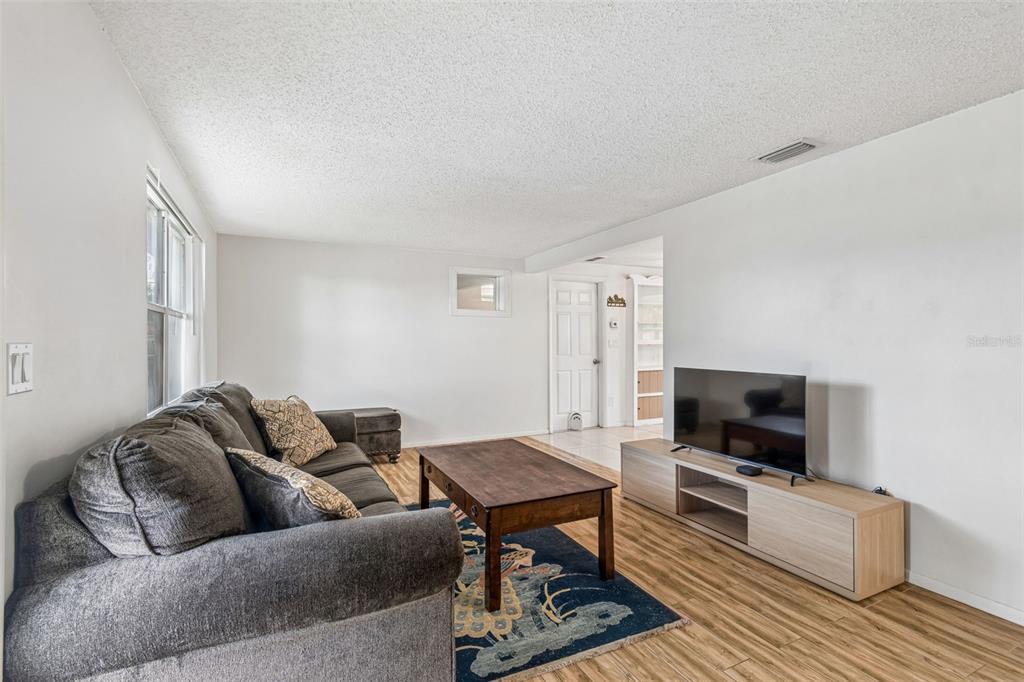 A living room features a gray sofa, a wooden coffee table, and a television console — 2440 ARCADIA ROAD, HOLIDAY, FL