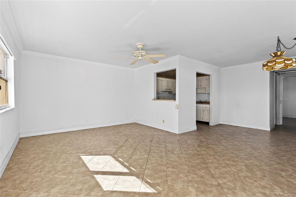 An empty room with beige tile flooring, white walls, a ceiling fan, and a pass-through window — 187 SAXONY TERRACE UNIT D, DELRAY BEACH, FL