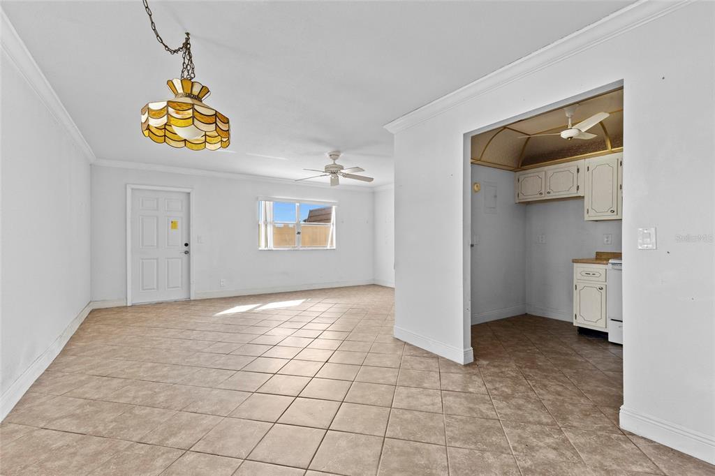 A tiled living room with a hanging lamp leads into a kitchen with white cabinets — 187 SAXONY TERRACE UNIT D, DELRAY BEACH, FL