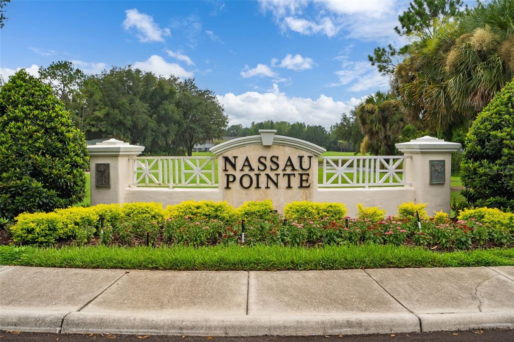 A stone monument sign for Nassau Pointe stands behind a landscaped garden and sidewalk — 18105 NASSAU POINT DRIVE, TAMPA, FL