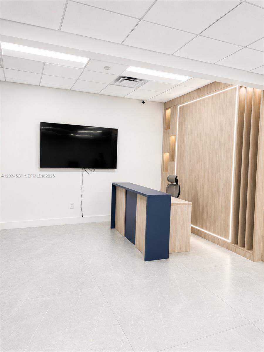 A modern office reception area features a blue and wood desk against a paneled wall — 1110 Ponce De Leon Blvd, Coral Gables FL 33134, CORAL GABLES, FL