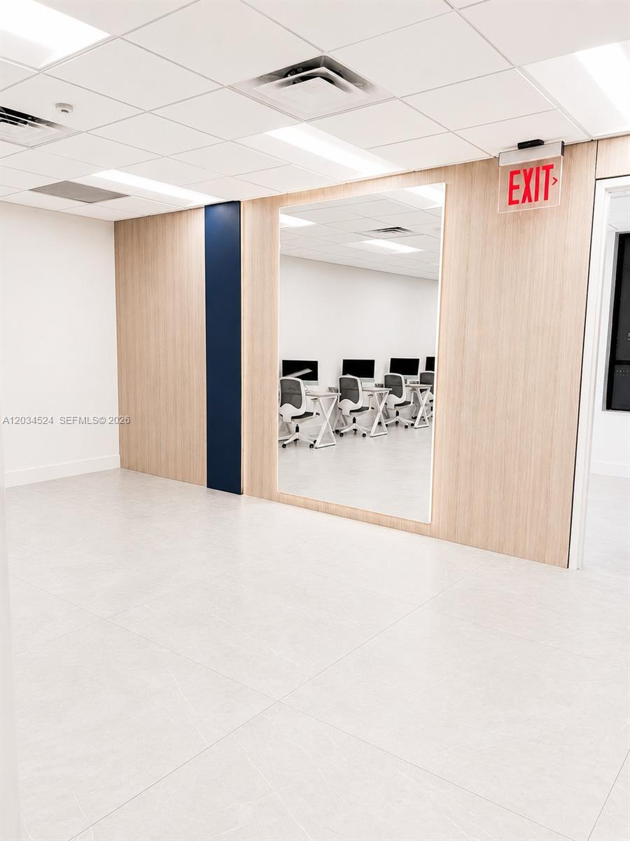 An office space features a large wall mirror, light wood paneling, and white tiled flooring — 1110 Ponce De Leon Blvd, Coral Gables FL 33134, CORAL GABLES, FL