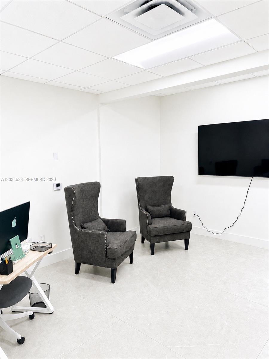 A modern office space features two dark gray wingback chairs, a desk, and a wall-mounted television — 1110 Ponce De Leon Blvd, Coral Gables FL 33134, CORAL GABLES, FL