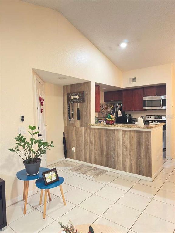 A kitchen with wood-look paneling on the breakfast bar and a tiled floor — 5100 CONROY ROAD UNIT 26, ORLANDO, FL