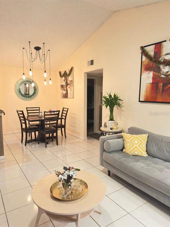 A living and dining area features white tile floors, a grey sofa, and pendant lighting — 5100 CONROY ROAD UNIT 26, ORLANDO, FL