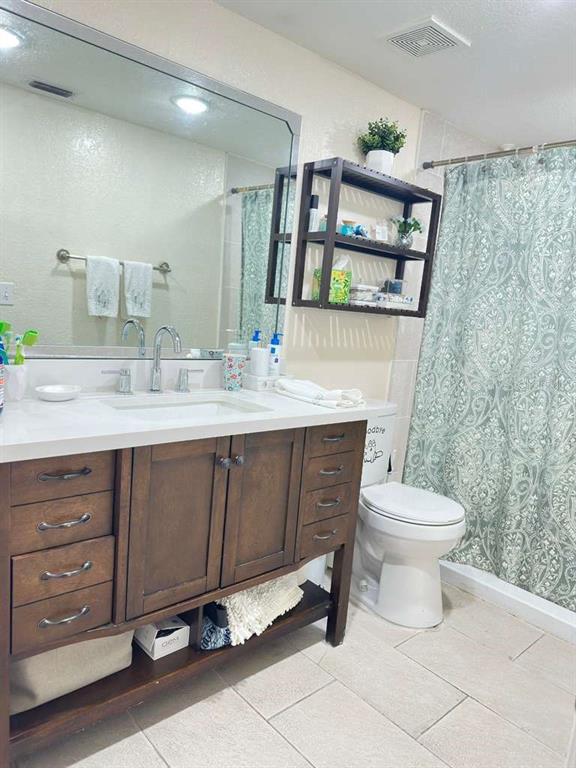 A bathroom features a wooden vanity with a white countertop, a mirror, and a shower curtain — 5100 CONROY ROAD UNIT 26, ORLANDO, FL