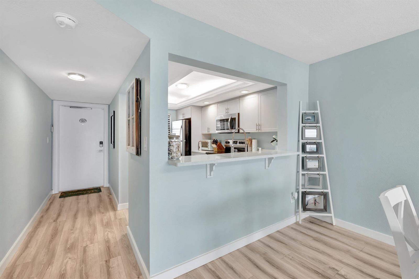 A light blue dining area features a breakfast bar pass-through window into the kitchen — 10310 S Ocean Drive # 305, Jensen Beach FL 34957, JENSEN BEACH, FL