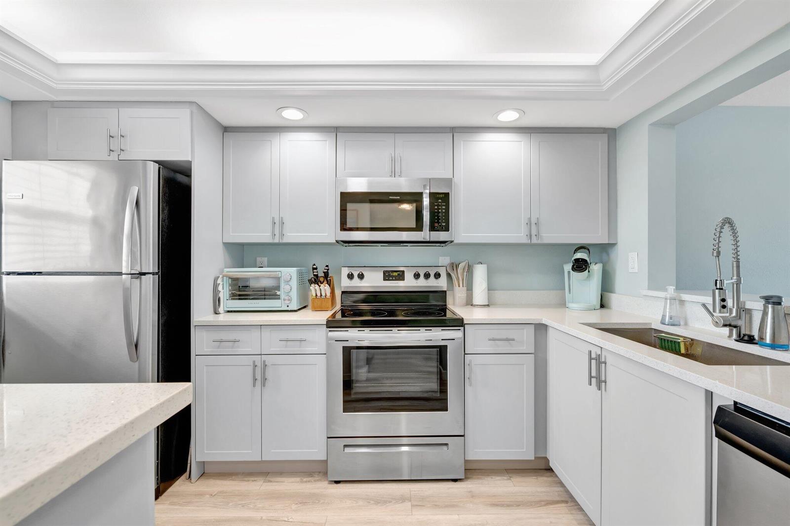 A kitchen with light gray cabinets, stainless steel appliances, and light-colored countertops — 10310 S Ocean Drive # 305, Jensen Beach FL 34957, JENSEN BEACH, FL