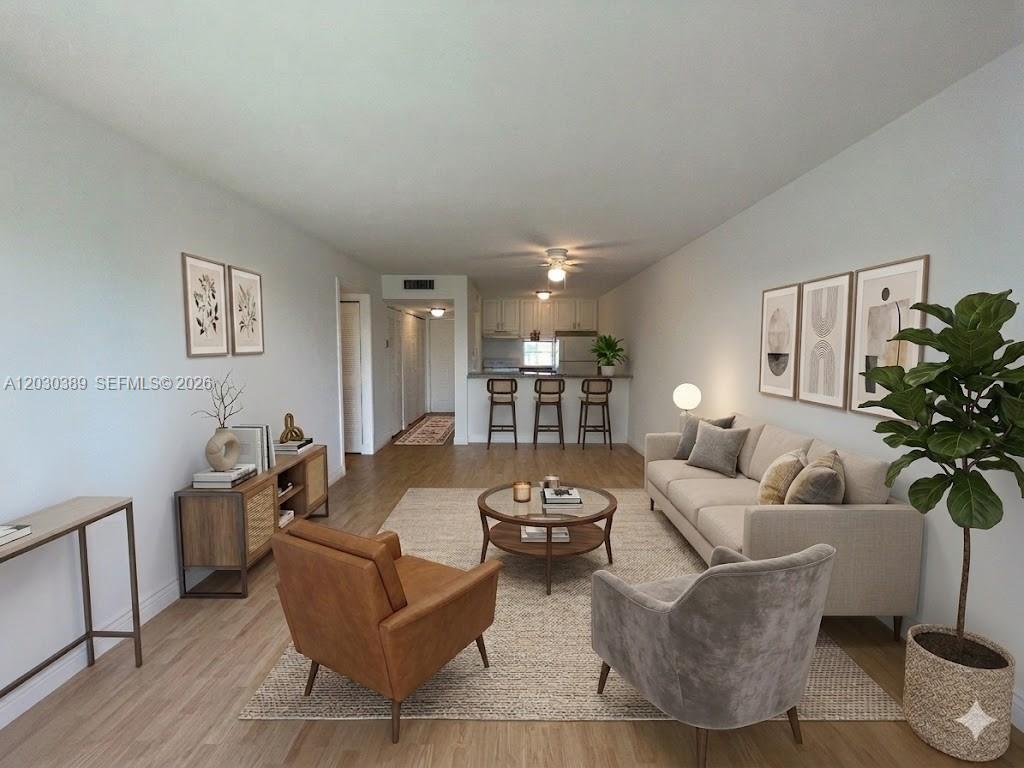 This is a rendering of a living room with a sofa, armchairs, and kitchen bar — 8560 N Sherman Cir # 504, Miramar FL 33025, MIRAMAR, FL