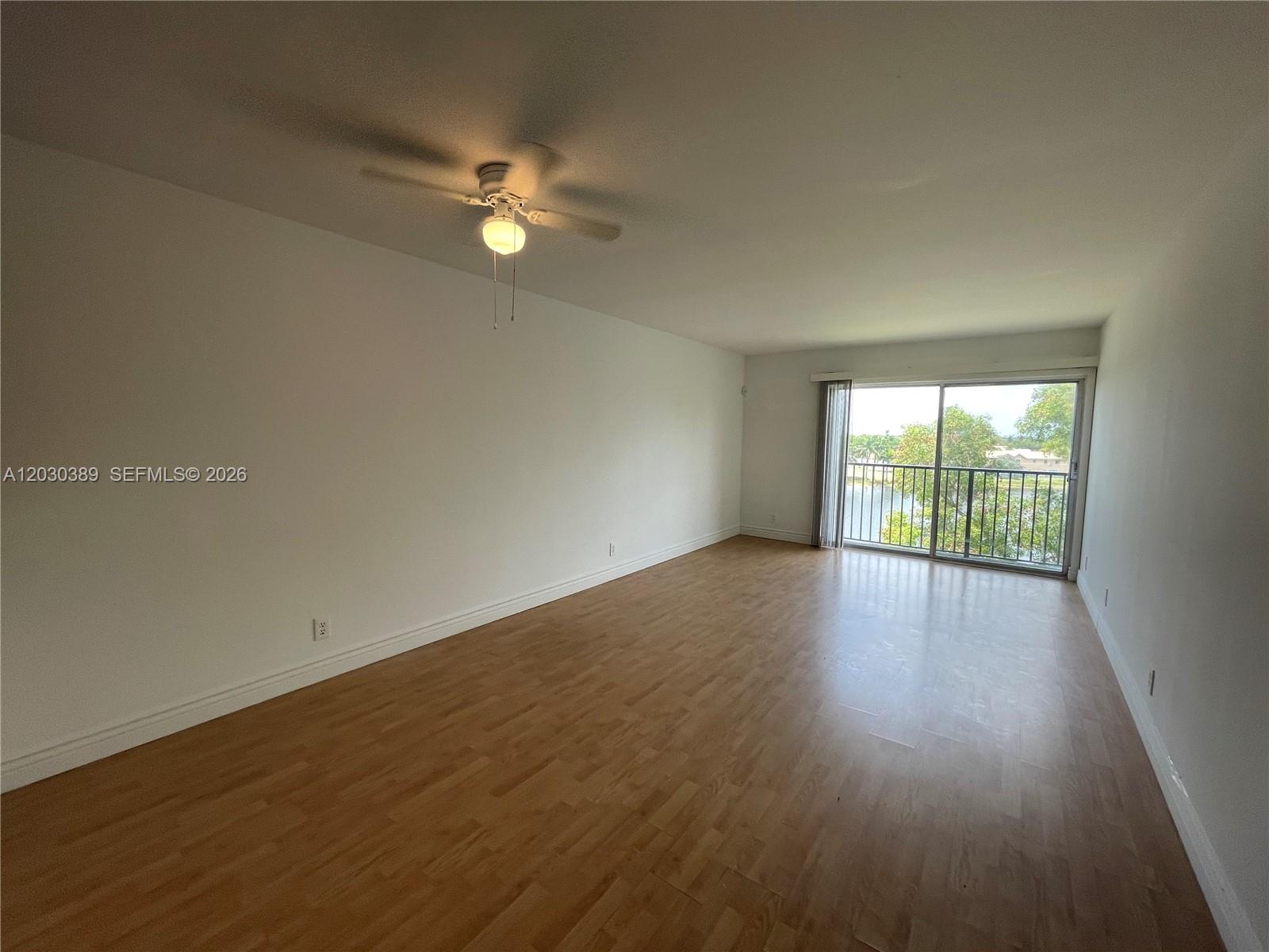 An empty room with light wood flooring, a ceiling fan, and a sliding glass door — 8560 N Sherman Cir # 504, Miramar FL 33025, MIRAMAR, FL