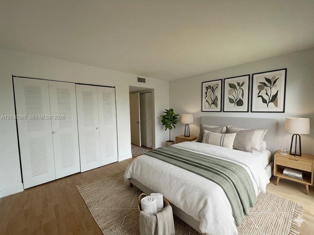 A bedroom features a bed with green bedding, wood nightstands, and white louvered closet doors — 8560 N Sherman Cir # 504, Miramar FL 33025, MIRAMAR, FL