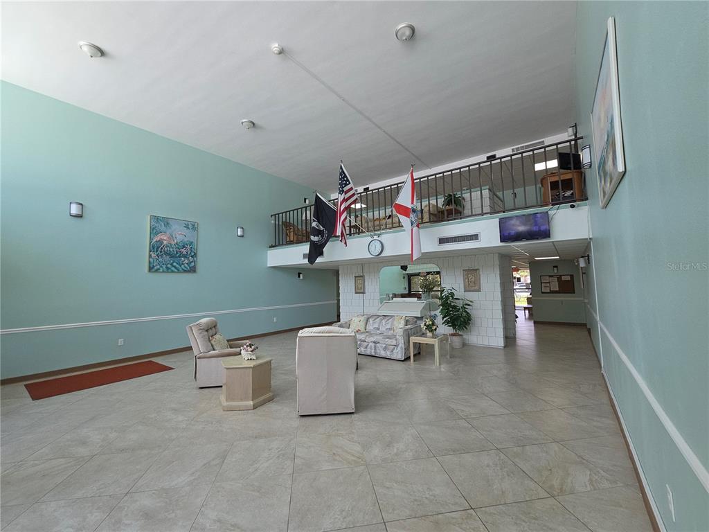 A spacious lobby features tile flooring, a high ceiling, and a mezzanine with flags — 21260 BRINSON AVENUE UNIT 307, PORT CHARLOTTE, FL