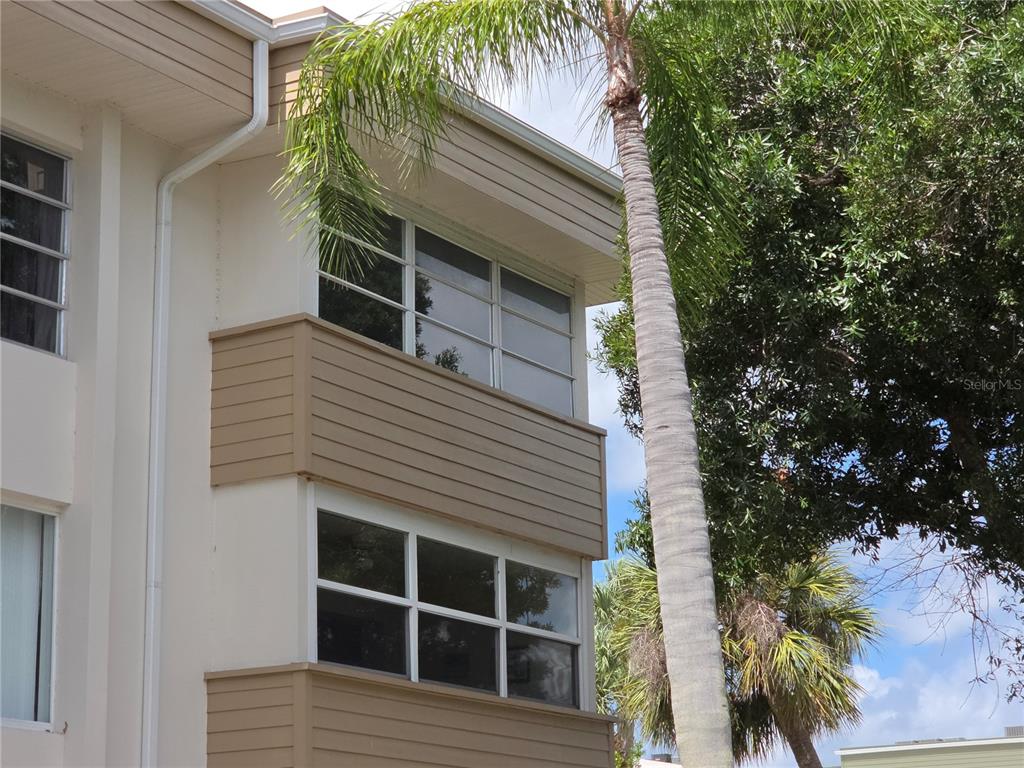 Exterior view of a multi-story building with tan horizontal siding and large windows — 21260 BRINSON AVENUE UNIT 307, PORT CHARLOTTE, FL