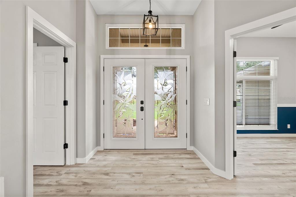 An entryway features double glass-paneled doors, light wood-look flooring, and a hanging lantern light fixture — 6245 SILVER OAKS DRIVE, ZEPHYRHILLS, FL