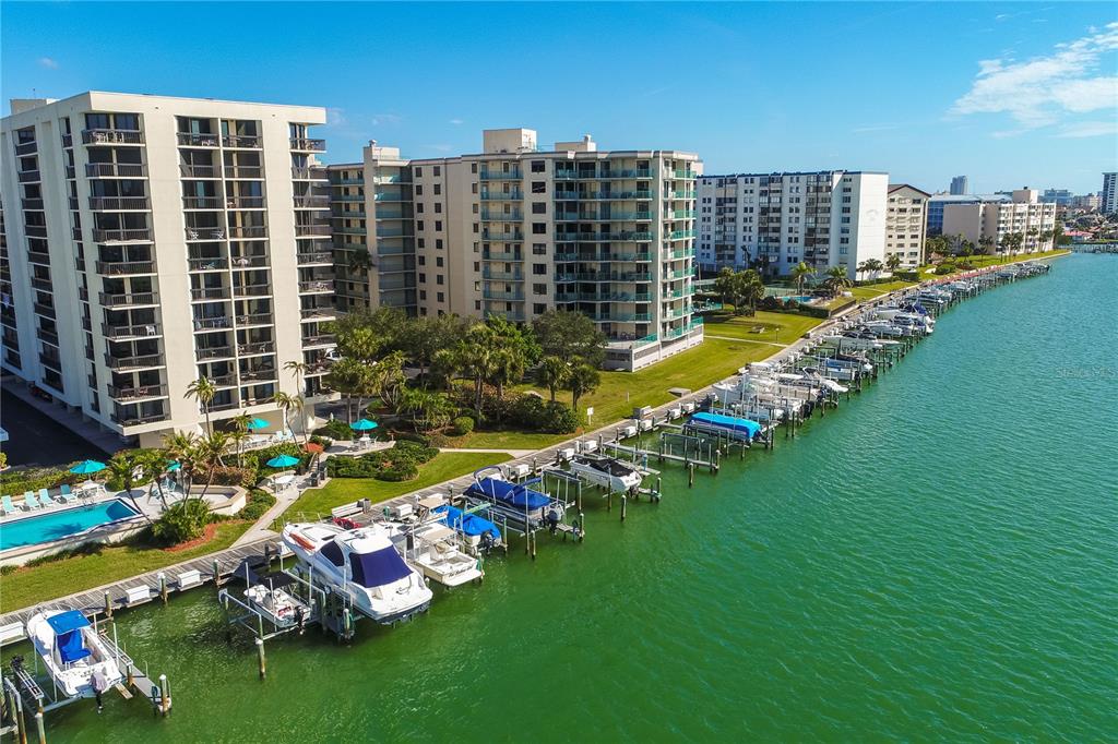 A multi-story apartment building stands behind a swimming pool with lounge chairs and umbrellas — 690 ISLAND WAY UNIT 408, CLEARWATER BEACH, FL