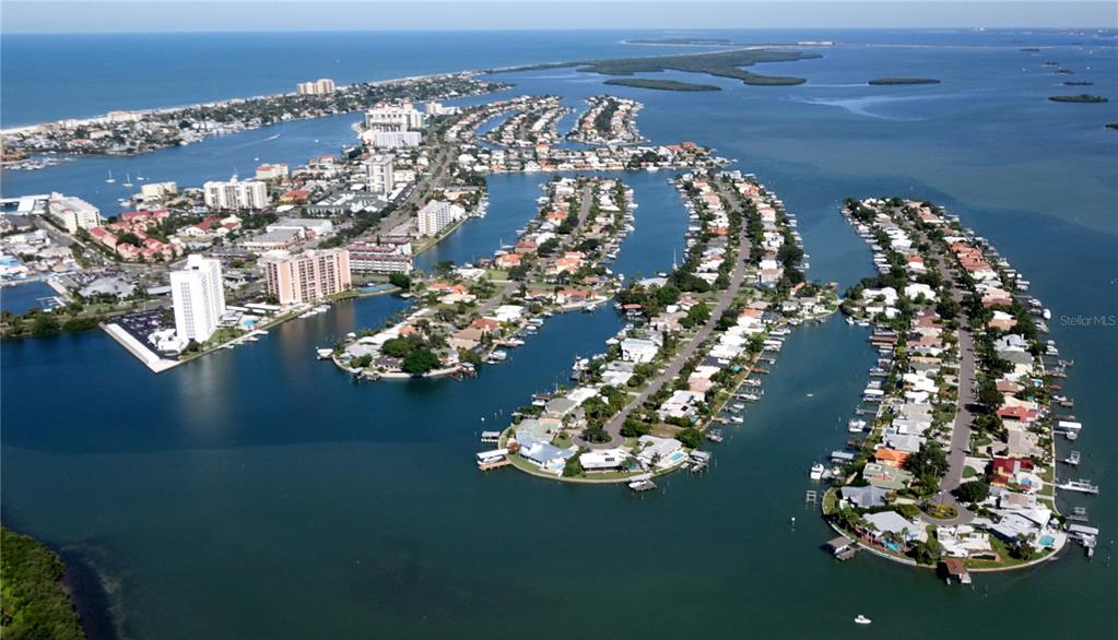 A bright living room and kitchen area features a boat-shaped coffee table and balcony view — 690 ISLAND WAY UNIT 408, CLEARWATER BEACH, FL