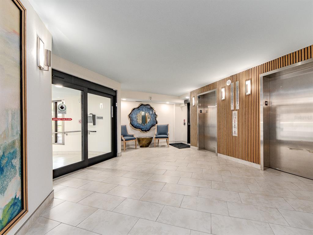 A living room features a boat-shaped coffee table, a white sofa, and a balcony view — 690 ISLAND WAY UNIT 408, CLEARWATER BEACH, FL