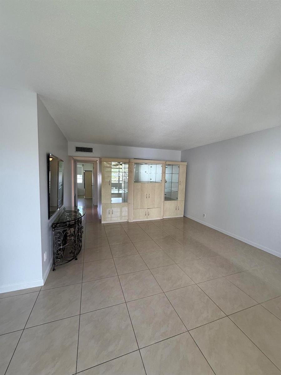 A living room features light-colored tile flooring, a built-in wall unit, and a decorative console table — 184 Easthampton H, West Palm Beach FL 33417, WEST PALM BEACH, FL