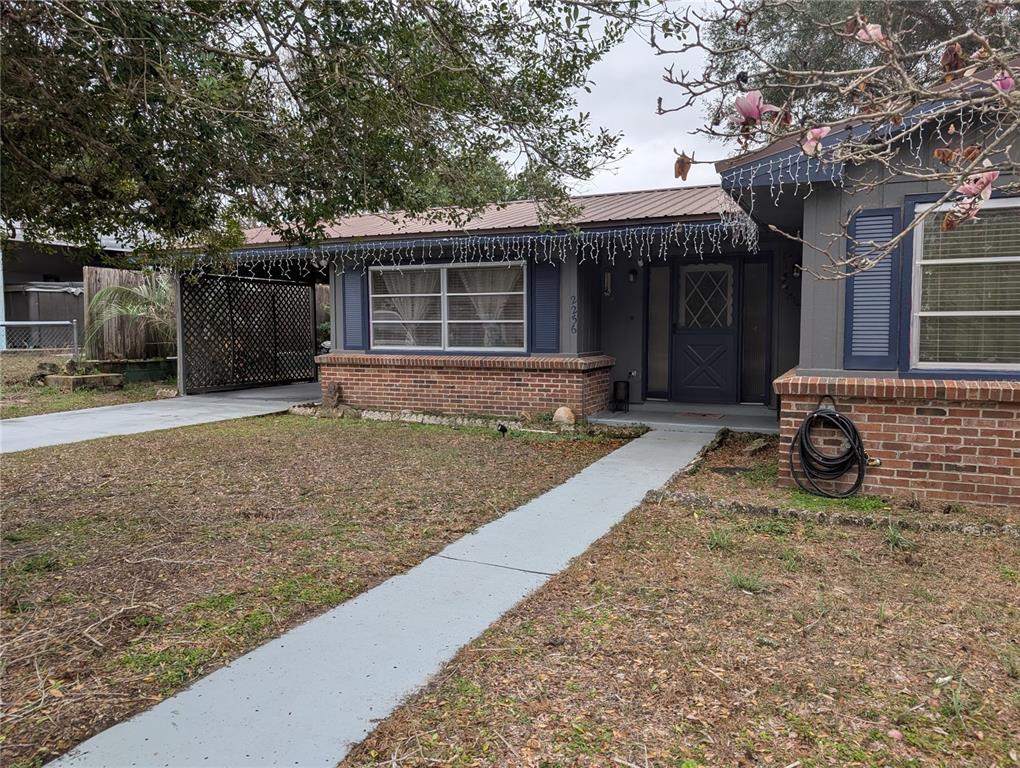 The exterior of a single-story brick house features a metal roof and a covered carport — 2256 W GREENWAY PLACE, CITRUS SPRINGS, FL