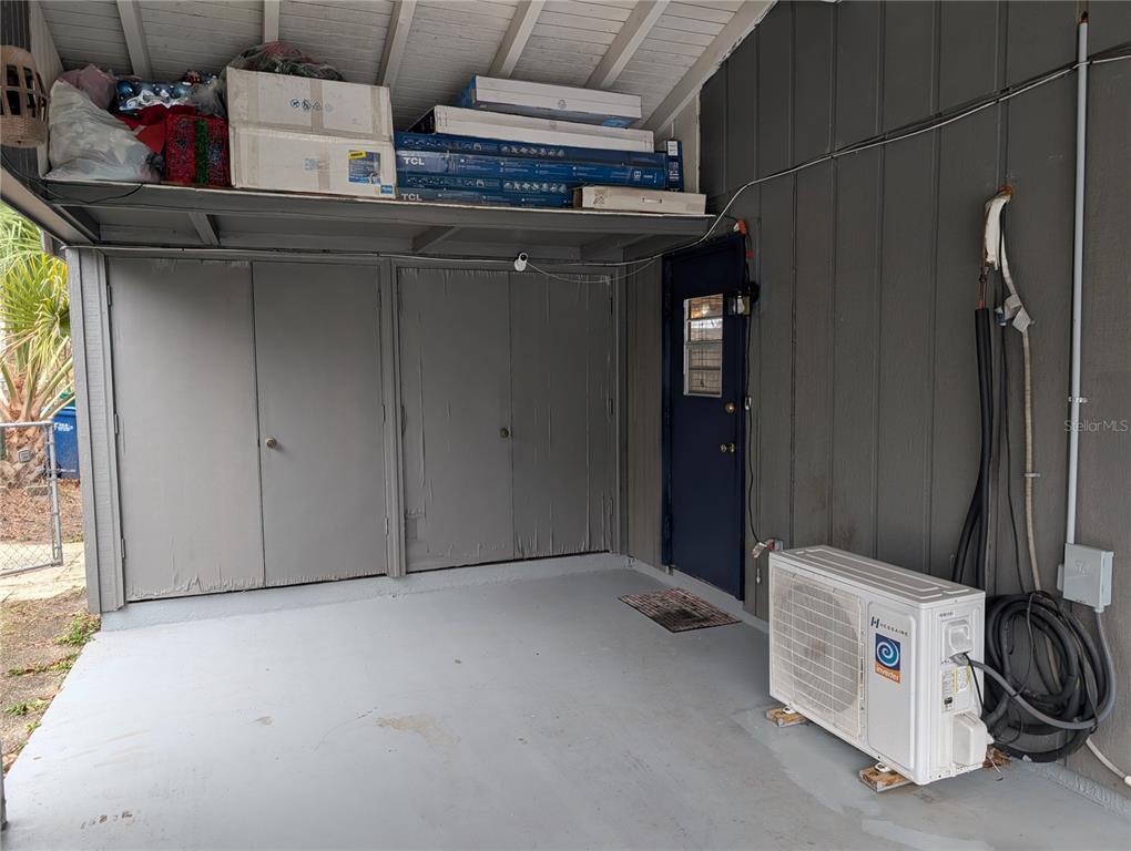 A covered carport area features gray storage cabinets, a blue door, and an outdoor HVAC unit — 2256 W GREENWAY PLACE, CITRUS SPRINGS, FL